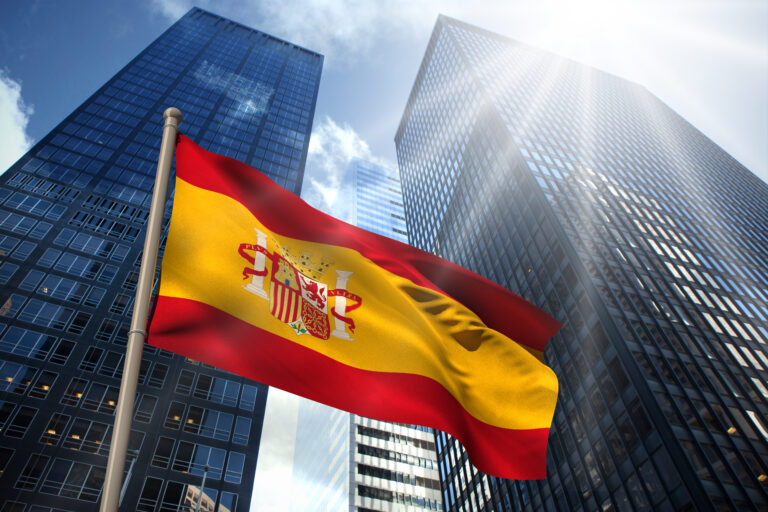 Spain,National,Flag,Against,Low,Angle,View,Of,Skyscrapers