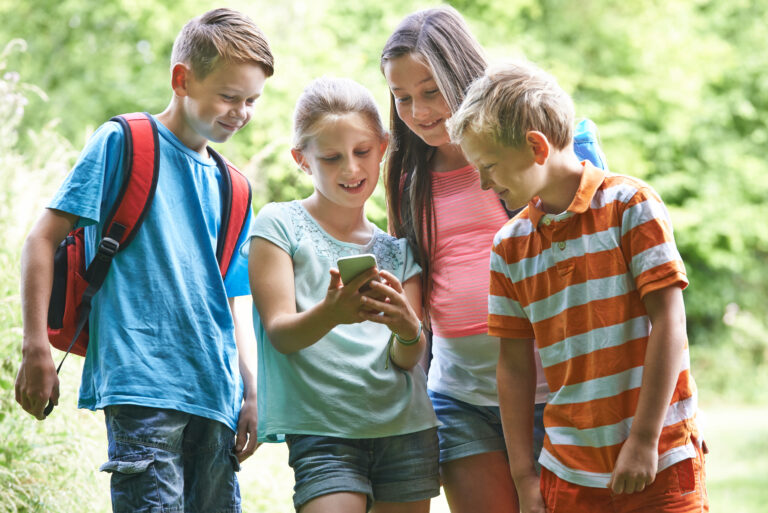 Group,Of,Children,Geocaching,Using,Mobile,Phone,In,Forest