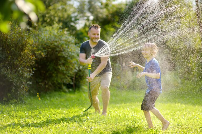 Funny,Little,Boy,With,His,Father,Playing,With,Garden,Hose